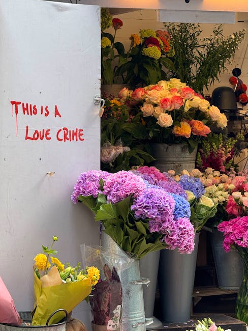 A flower shop display featuring a variety of fresh floral arrangements in different vases and containers. Prominently, there are large bouquets of pink and purple hydrangeas in clear plastic wrapping 