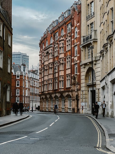The image shows a quiet street scene in Aldersgate Street, London, with a row of historic Victorian and Georgian-style buildings featuring detailed facades, large sash windows, and decorative stone wo