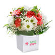 As if gathered fresh from the peaceful gardens near Barbican's Fortune Street Park, this bouquet overflows with a joyful energy: coral and soft peach carnations open in lush frills, their hues radiant under gentle natural light. Sprightly white daisies with bright green-yellow centers lend an uplifting charm, while sprigs of airy baby's breath drift gracefully between the larger blooms. The deep green foliage arcs elegantly around the base, giving structure and a sense of abundance, while tiny purple-tipped buds add a dash of mystery and anticipation to the composition. All the flowers are thoughtfully arranged in a crisp white, square gift bag, its handles ready to carry this touch of floral happiness to a special event or doorstep nearby. The image's clean background and focused lighting celebrate every petal and leaf, hinting at Barbican's blend of creativity and community. Perfect for birthdays, new beginnings, or any moment that calls for a sincere, beautifully presented gift across EC1, this bouquet captures the artful joy and local spirit of the area.